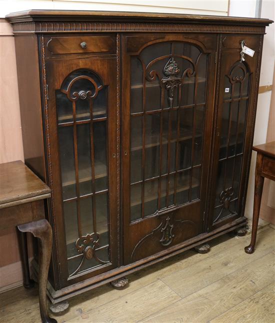 A walnut bookcase enclosed by three barred doors W.143cm